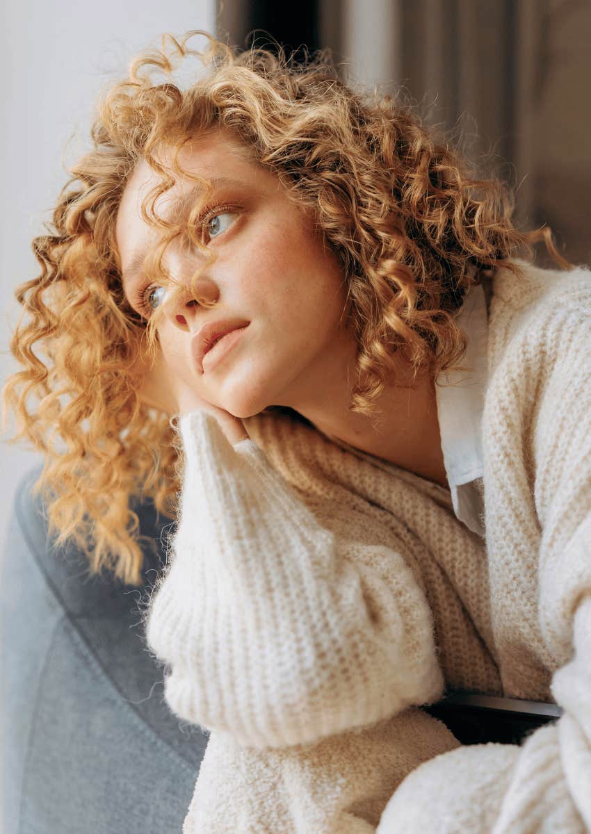 pensive young woman looking out of window