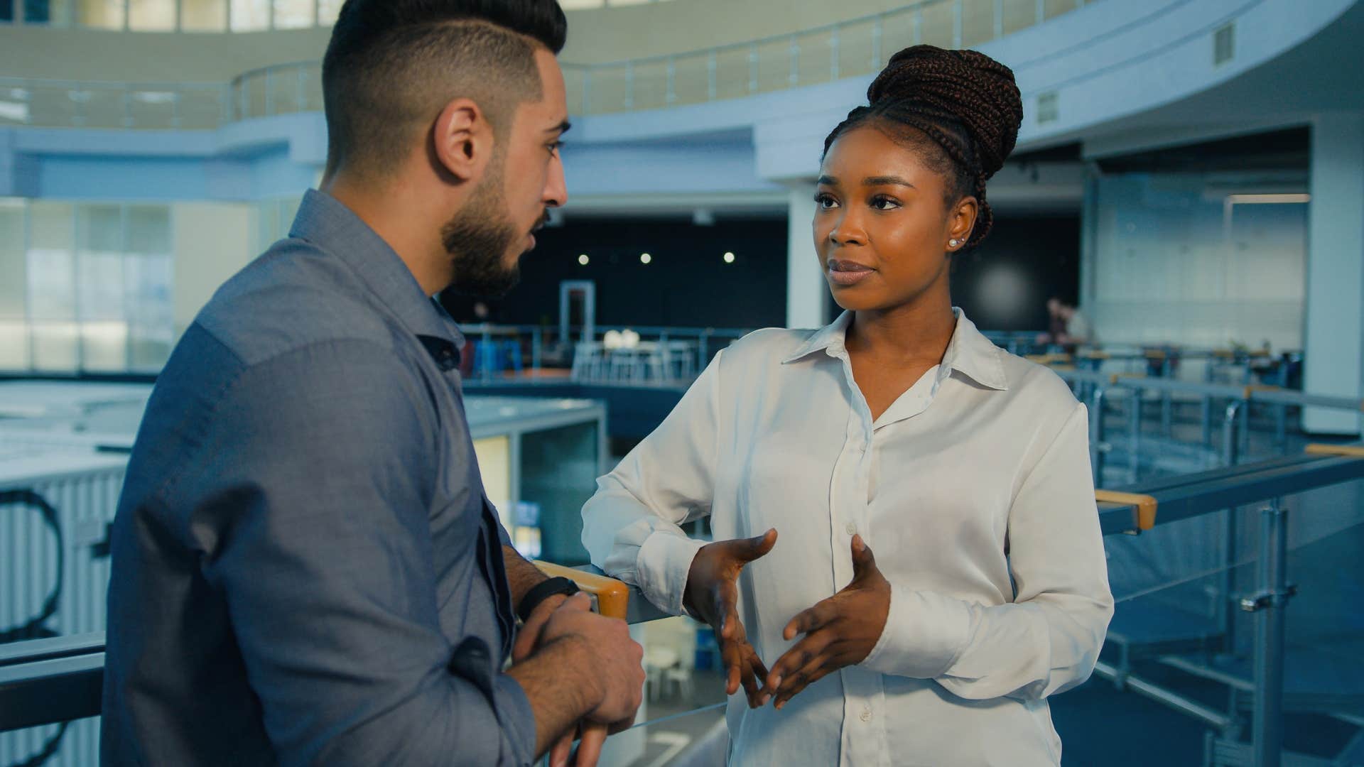 woman in white shirt having assertiveness as she talks to male coworker in blue