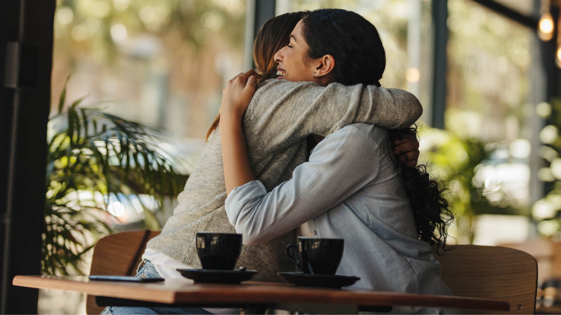 friend hugging friend at cafe as she has emotional awareness