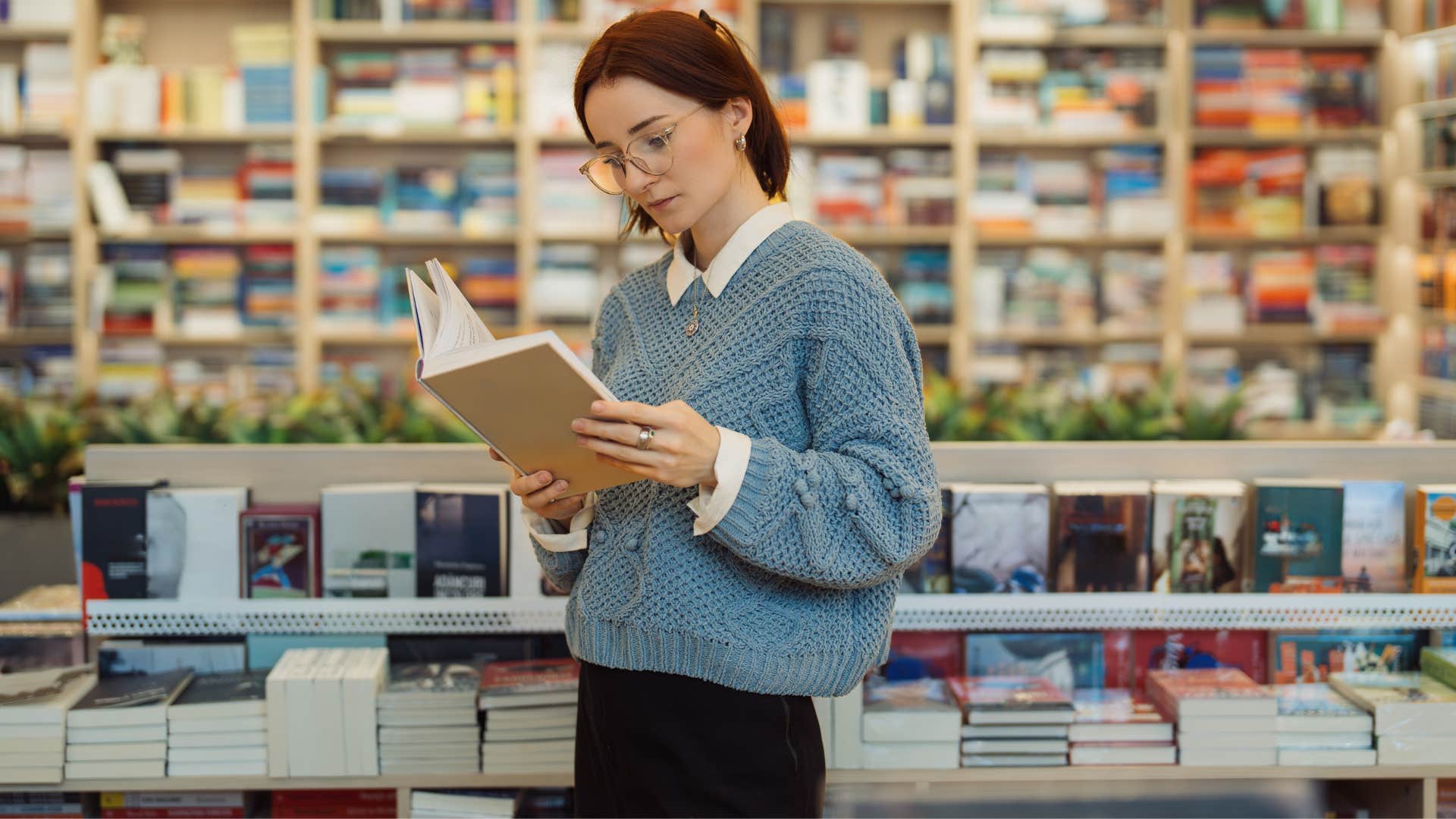 woman in blue sweater reading book as she has intellectual curiosity