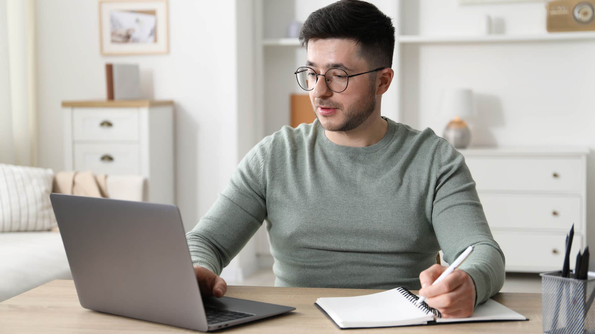 man in gray shirt being a perfectionist as he writes notes