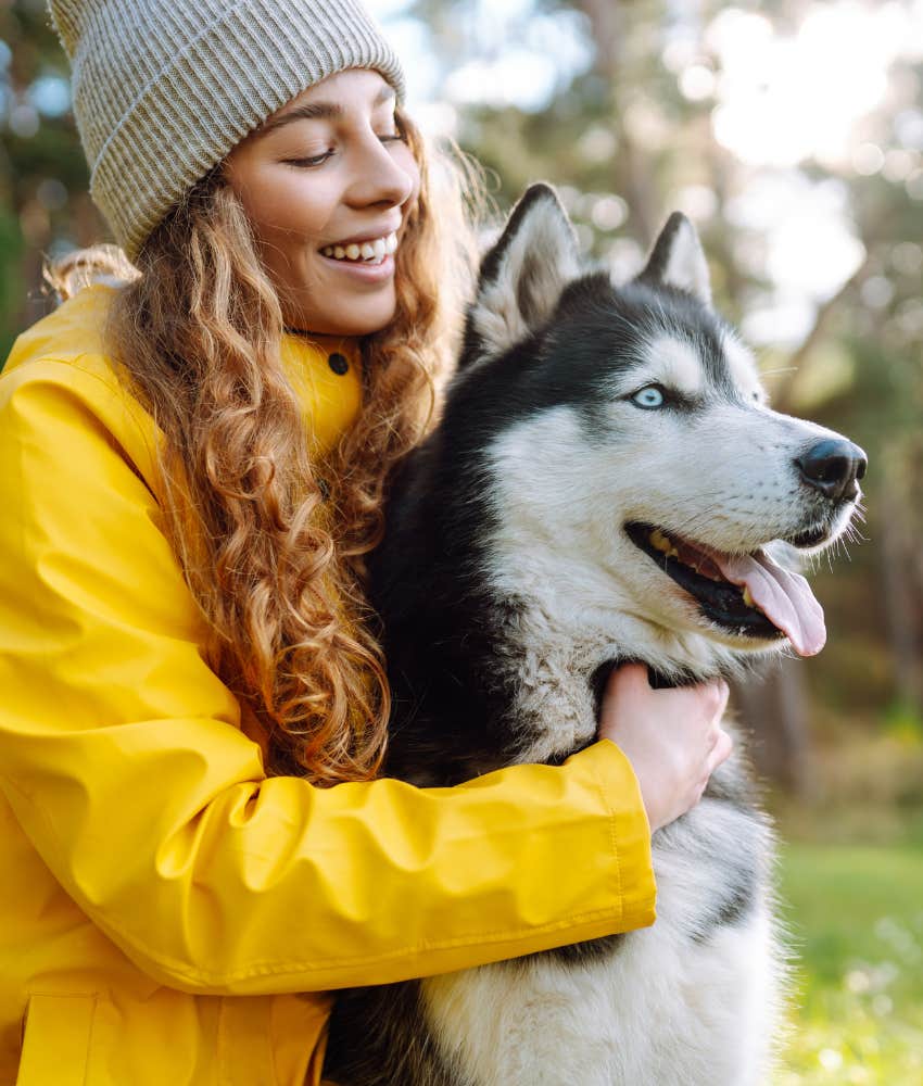 Woman in a raincoat hugging her dog 