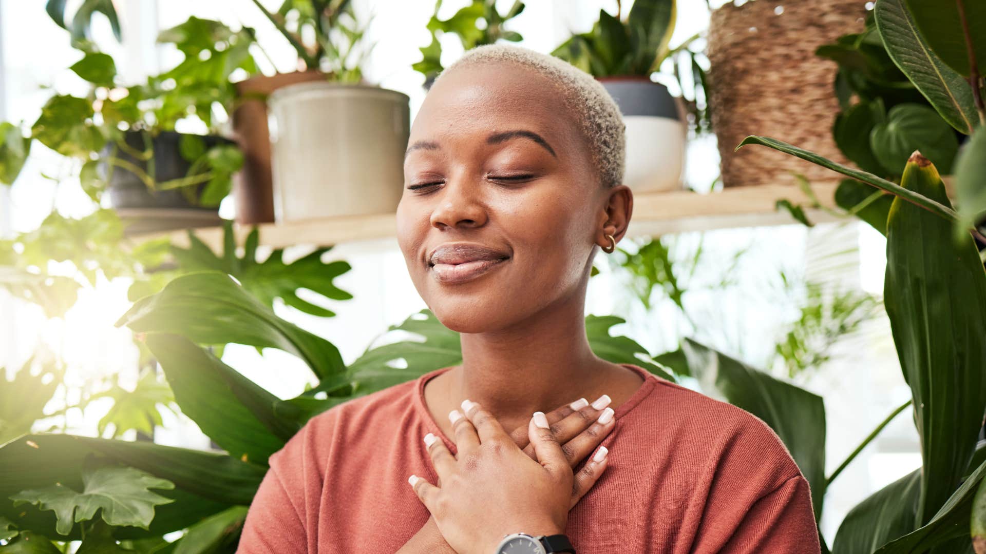 woman in orange shirt being self attuned as she meditates
