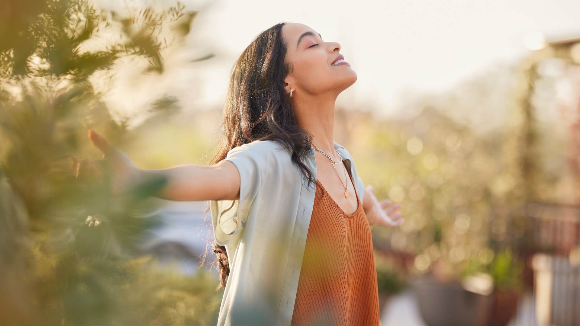 woman in orange shirt free spirited as she deep breaths outside