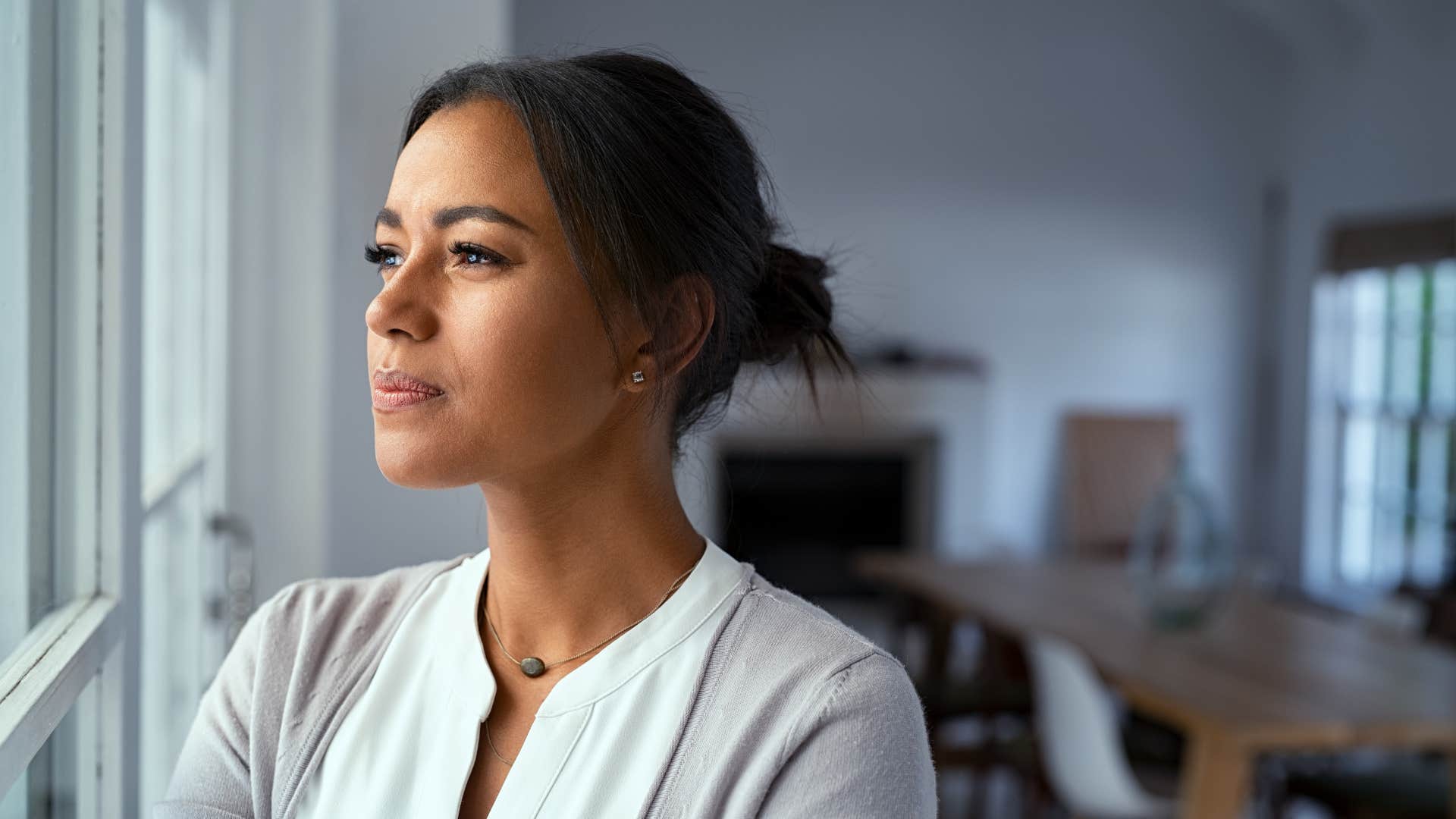 woman in white shirt highly aware as she stares out window