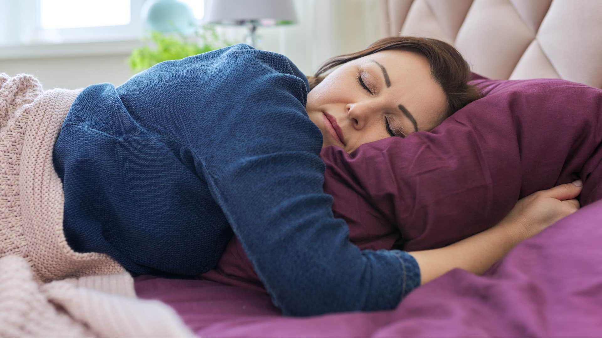 woman in blue shirt being a routine minimalist as she lays in bed lazily
