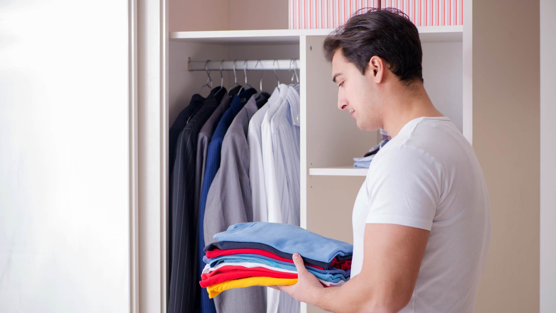 man with a practical wardrobe putting clothes away