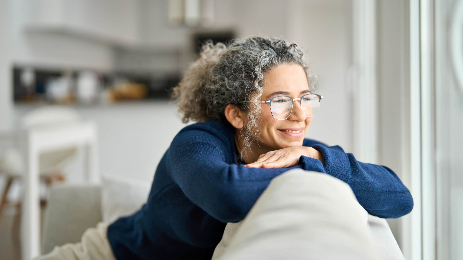 woman smiling on her couch in comfortable clothes