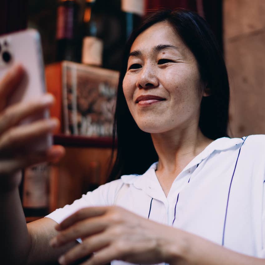 Naturally intuitive woman smiling at her phone outside