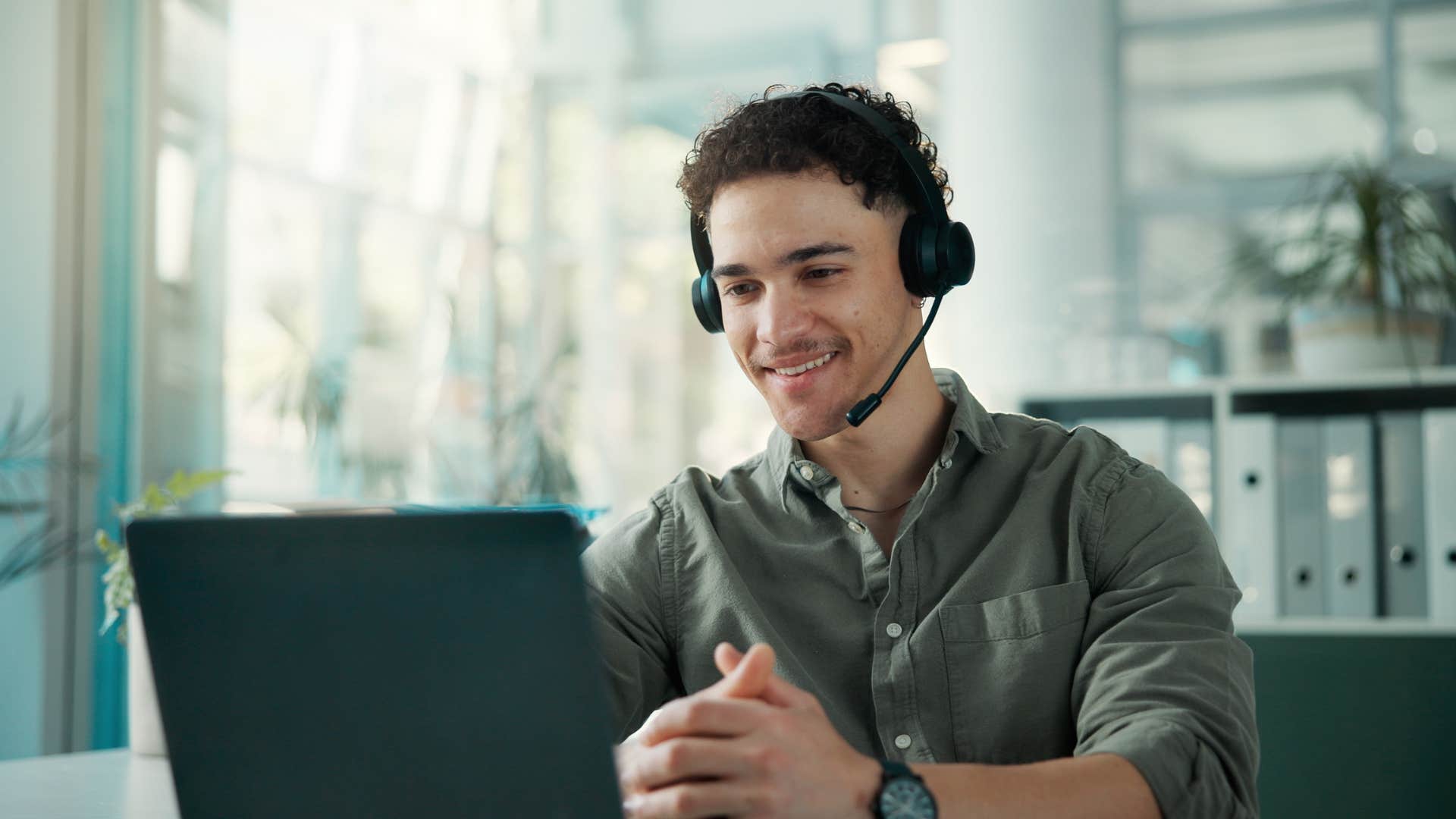 constantly overbooked man working on laptop while wearing headset
