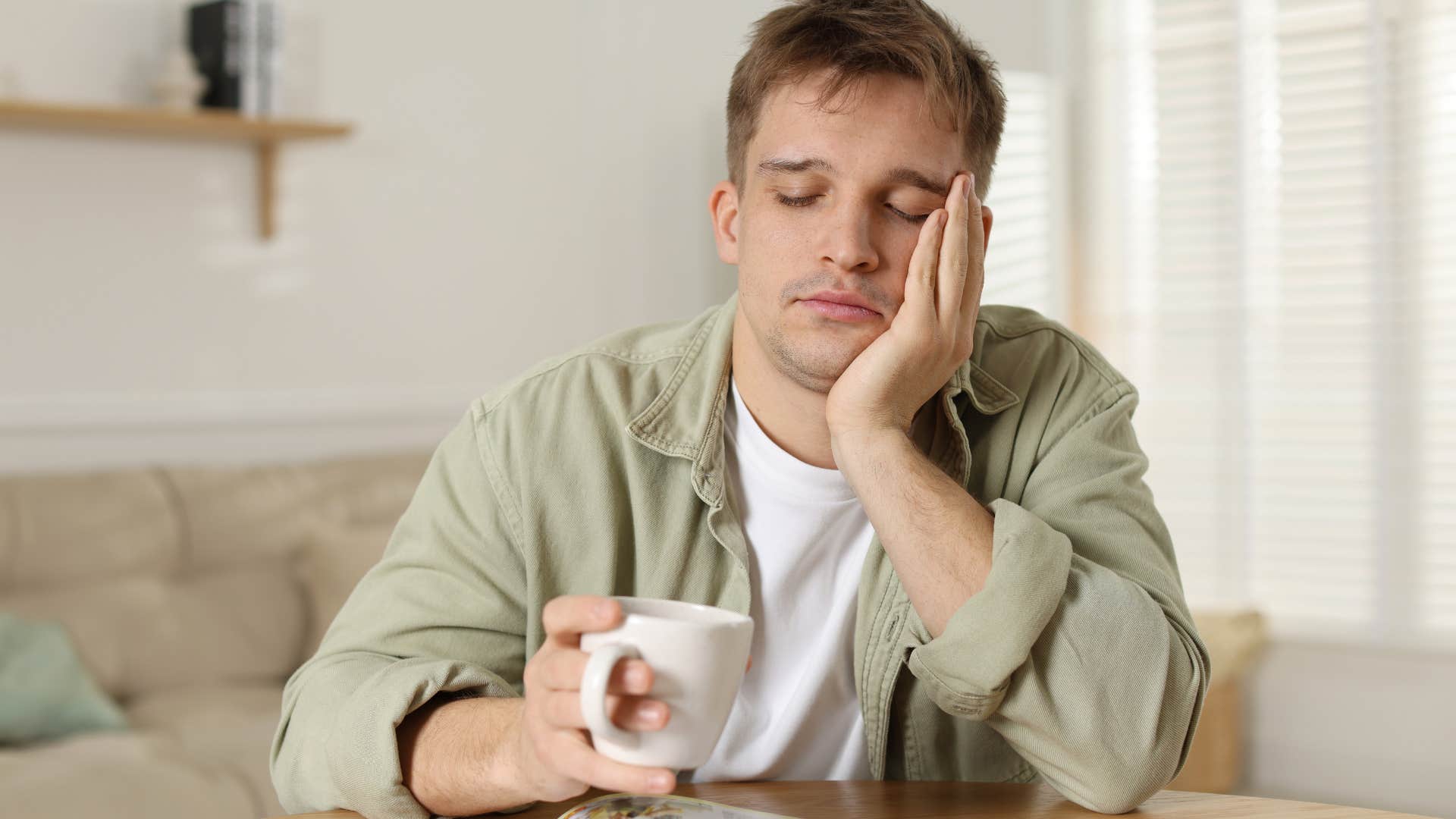 exhausted man struggles with decision fatigue sitting at table with mug
