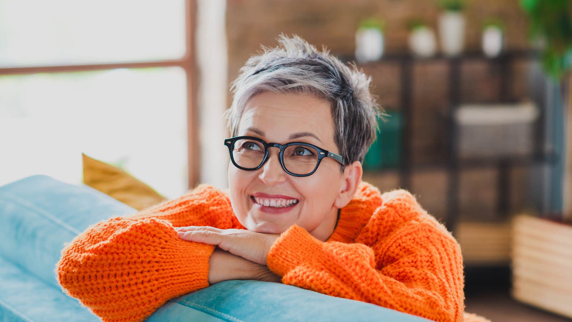 emotionally idealistic woman daydreaming while leaning over back of couch