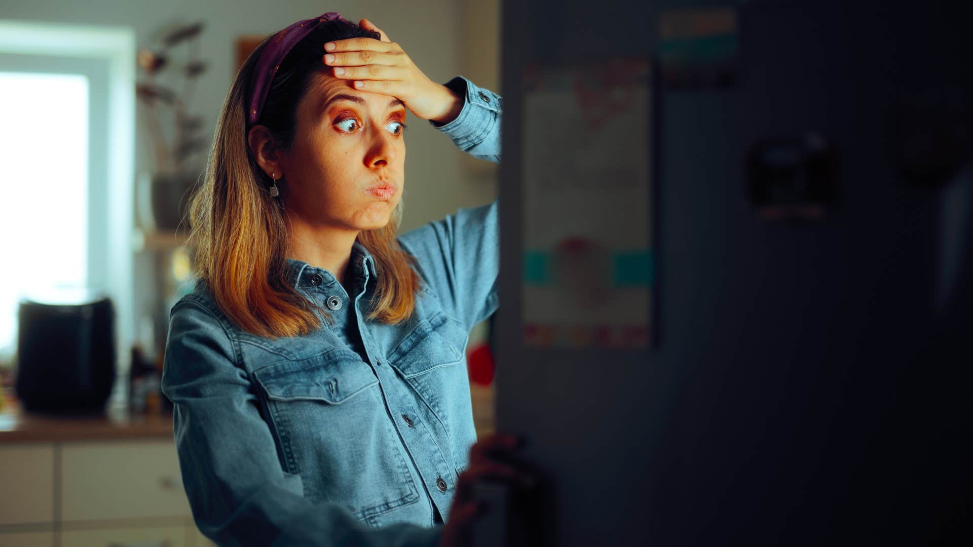 mildly forgetful woman opening the fridge