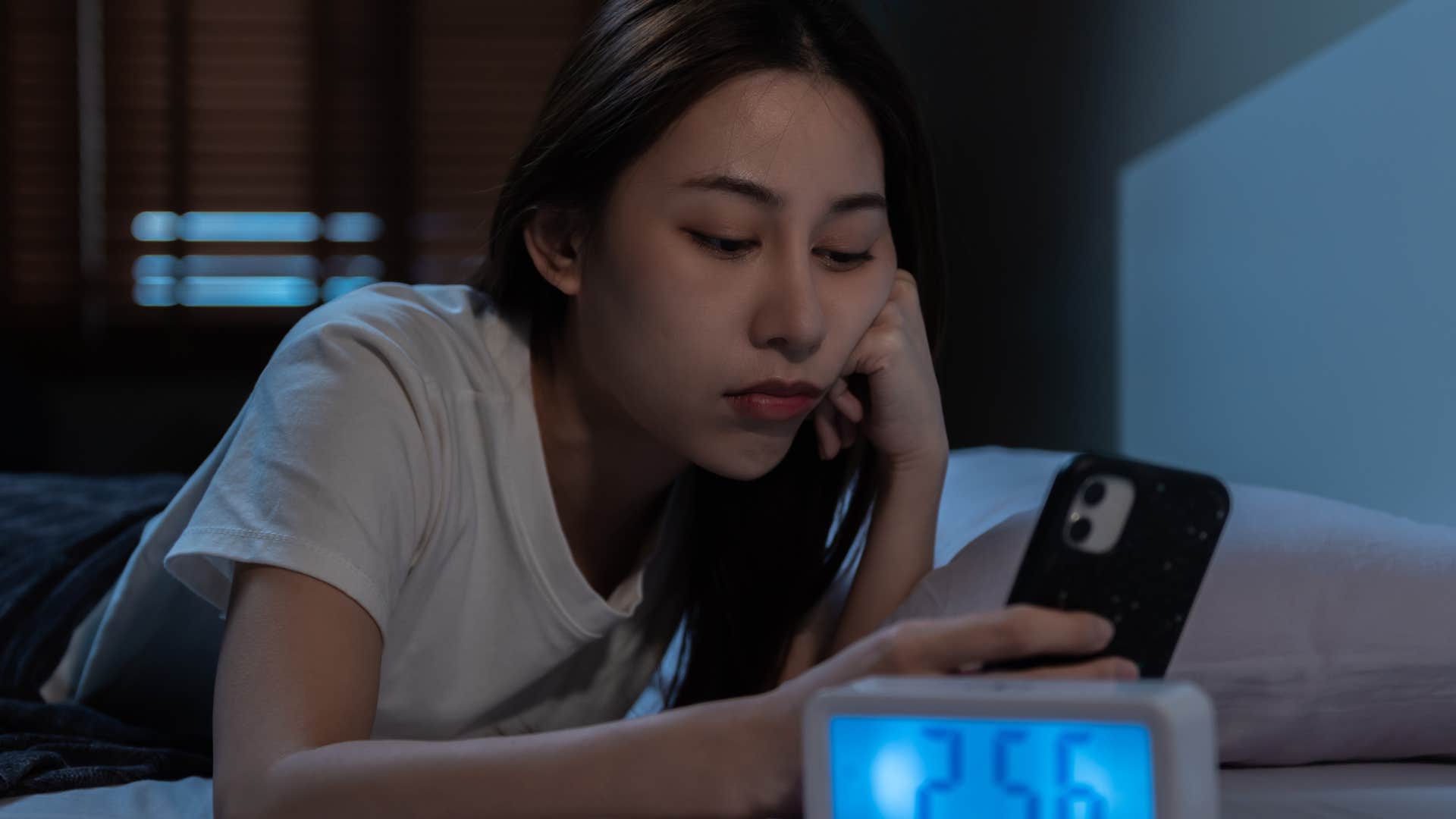 extroverted woman looking at her phone at night in bed