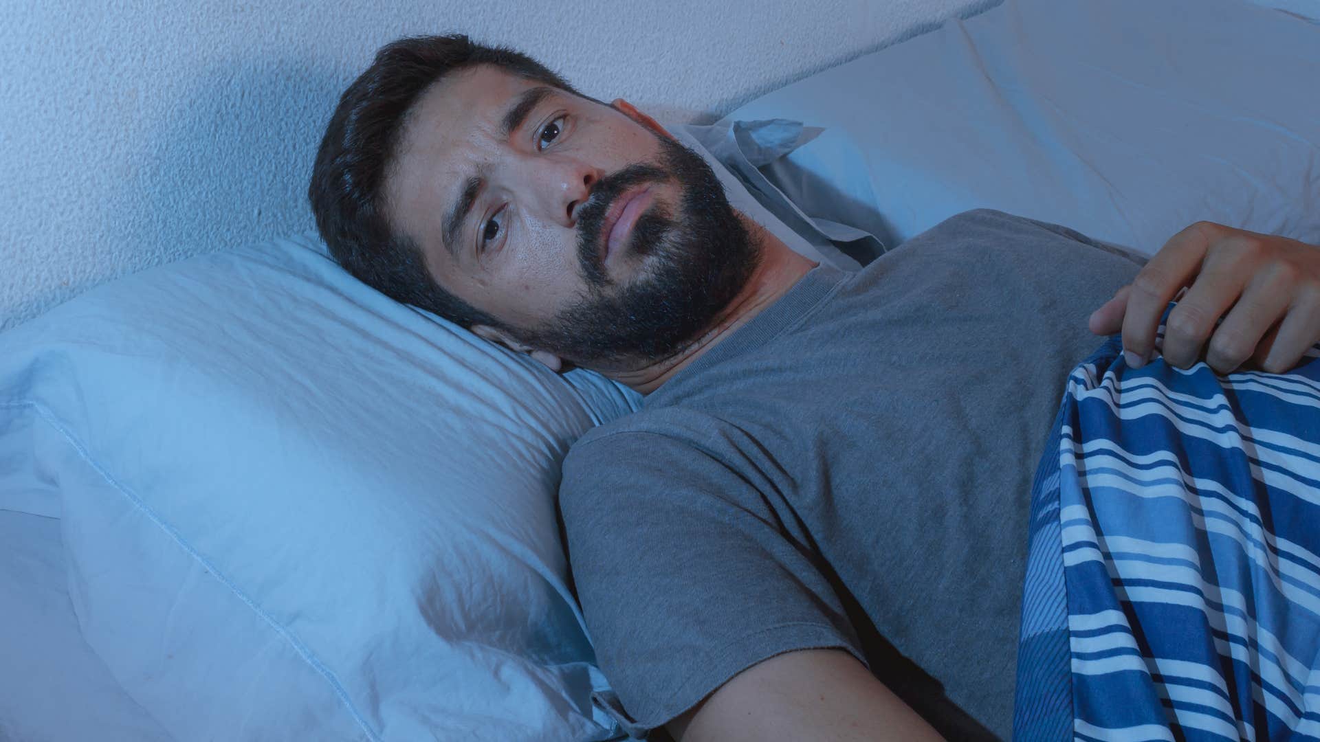 man who has low self-esteem laying awake in bed at night