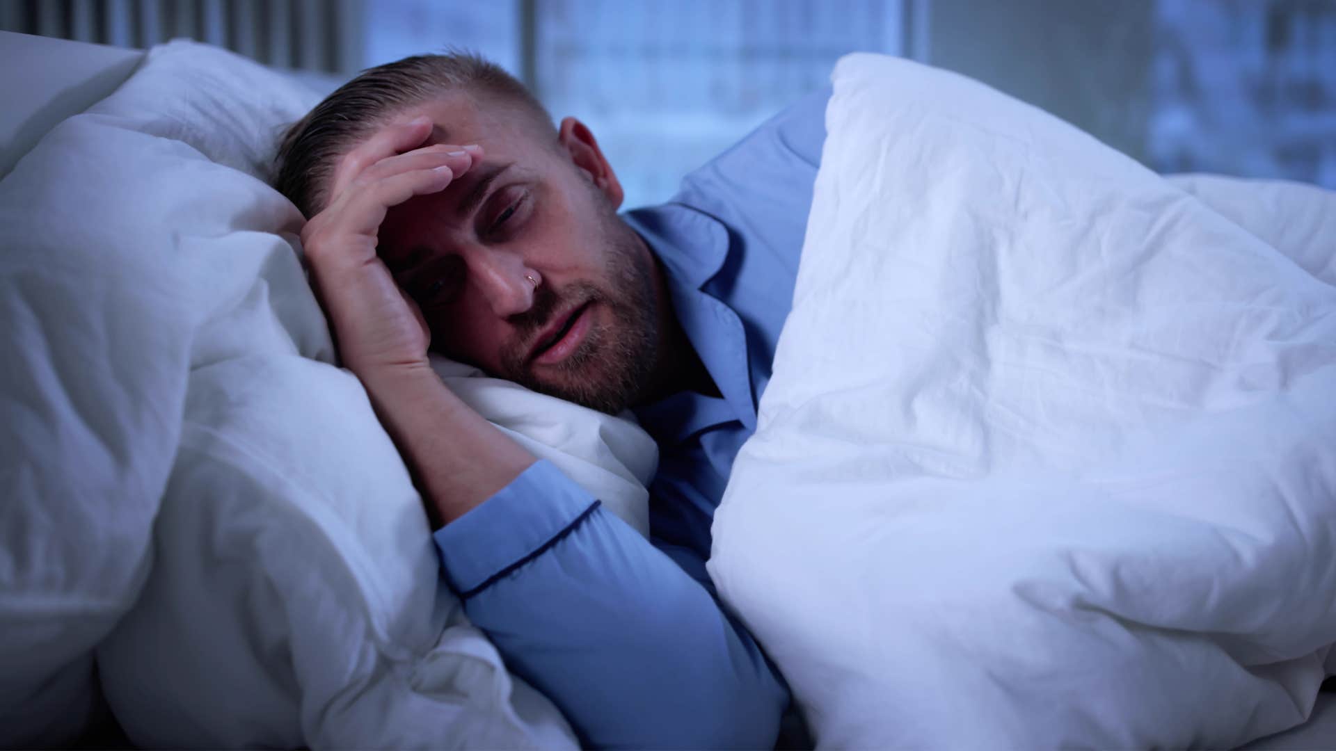 imaginative man lying awake in the dark at home alone