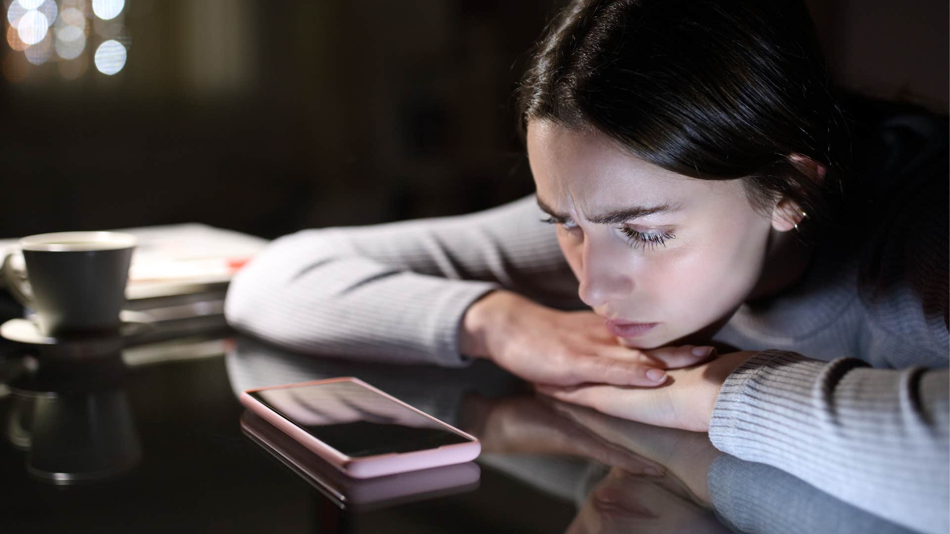 lonely woman looking at her phone at night