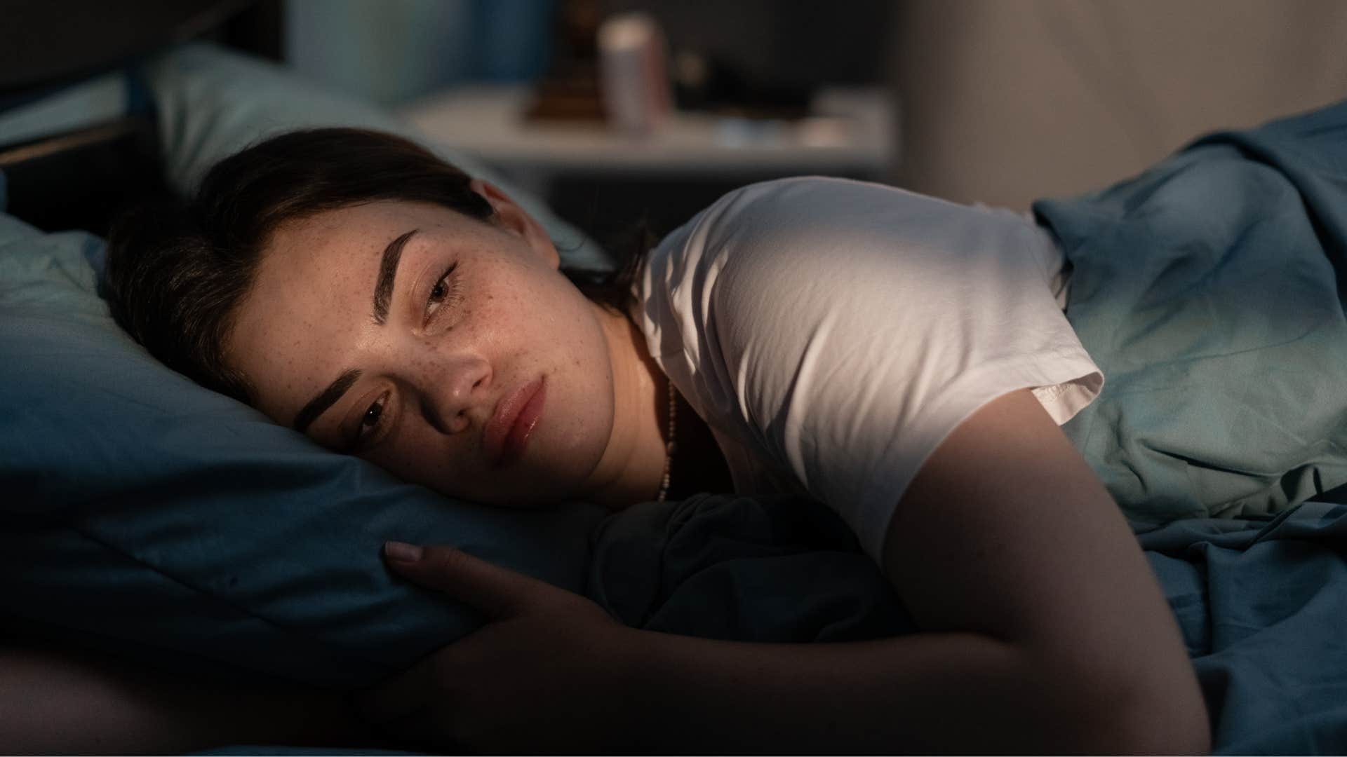 exhausted woman lying awake at night in bed