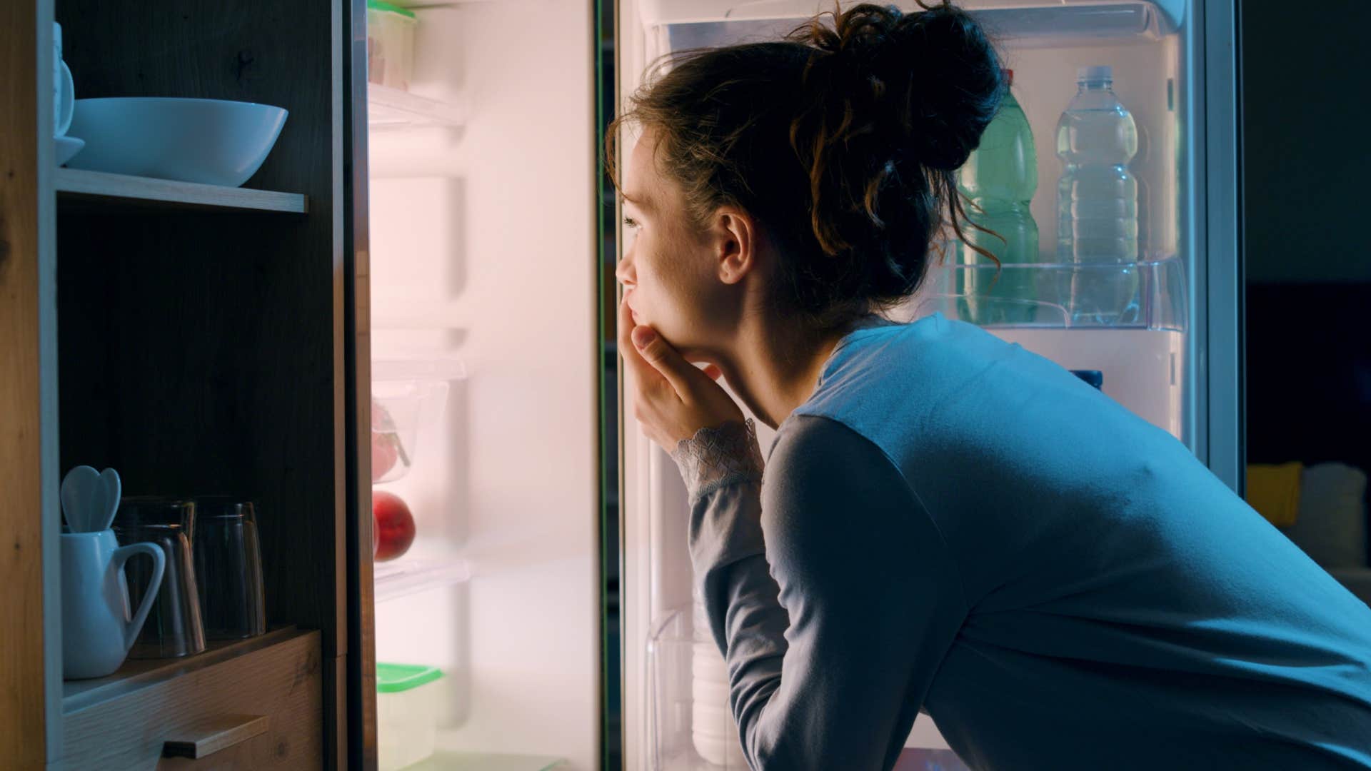 woman about to eat a big meal before bed looking in the fridge