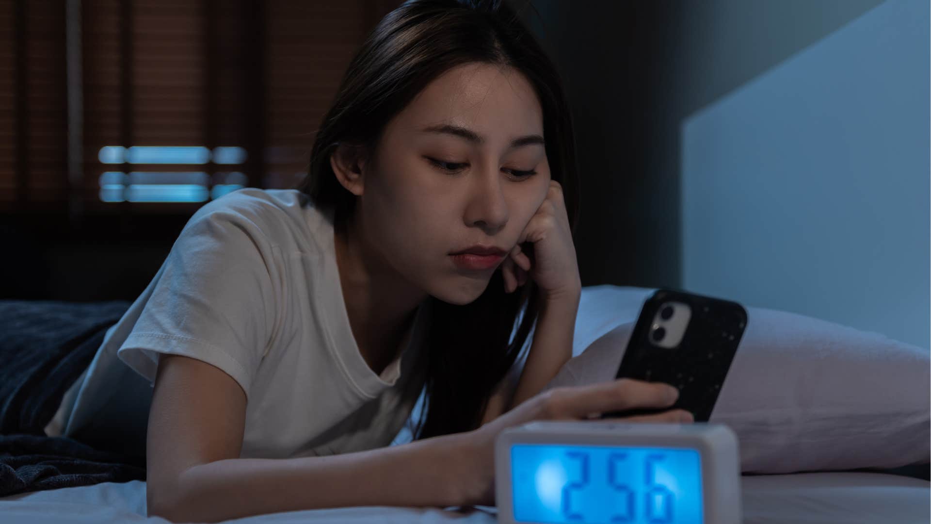 woman scrolling on her phone pushing off her bedtime