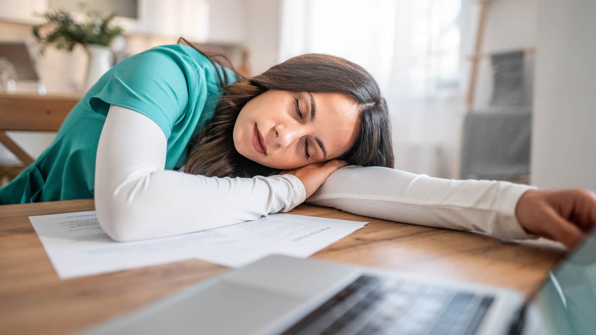 Woman who's easily burnt out asleep at her laptop.