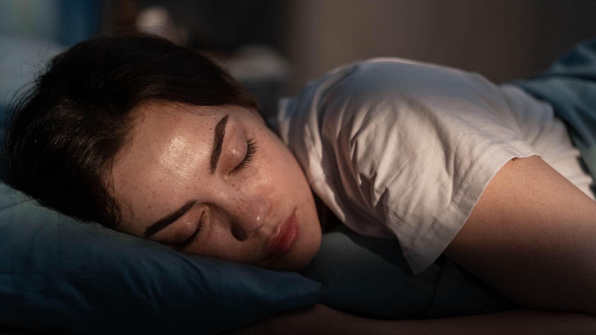 Woman who's a minimalist sleeping in a dark room.