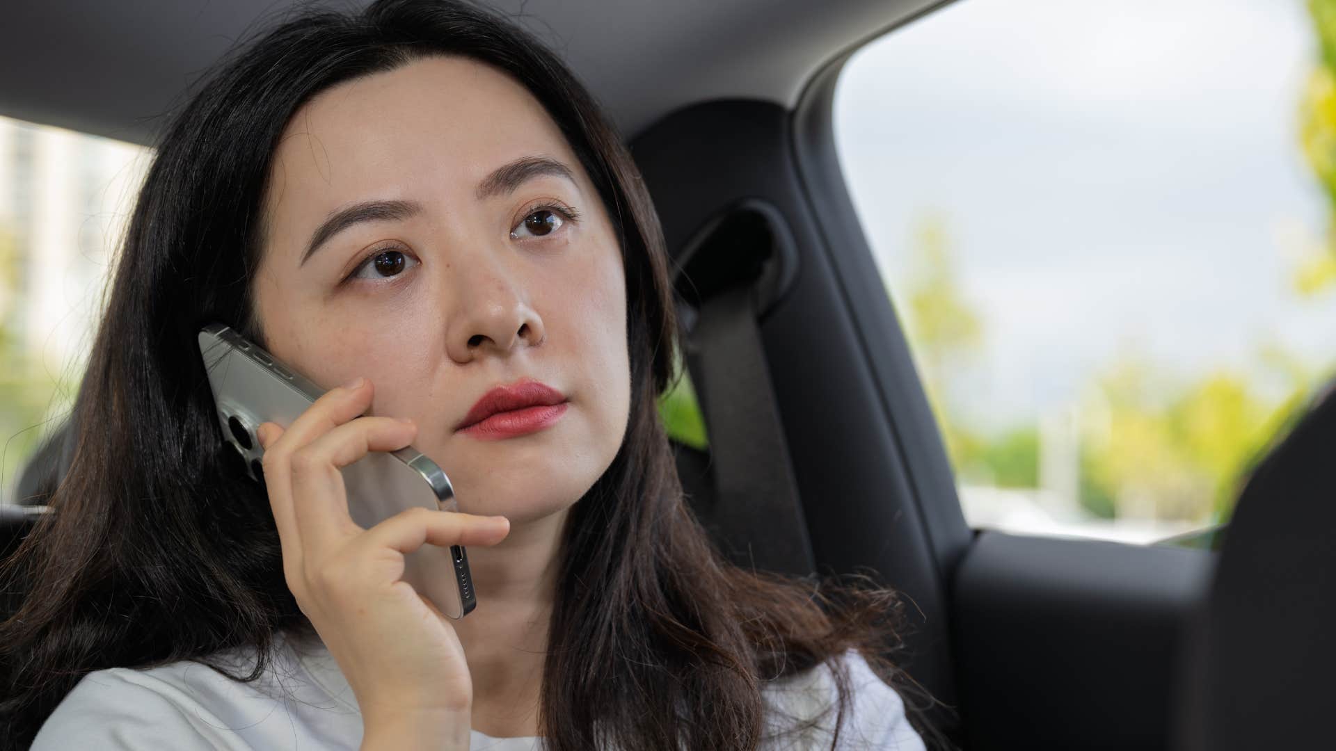 Woman who's a deep thinker talking on the phone in her car.