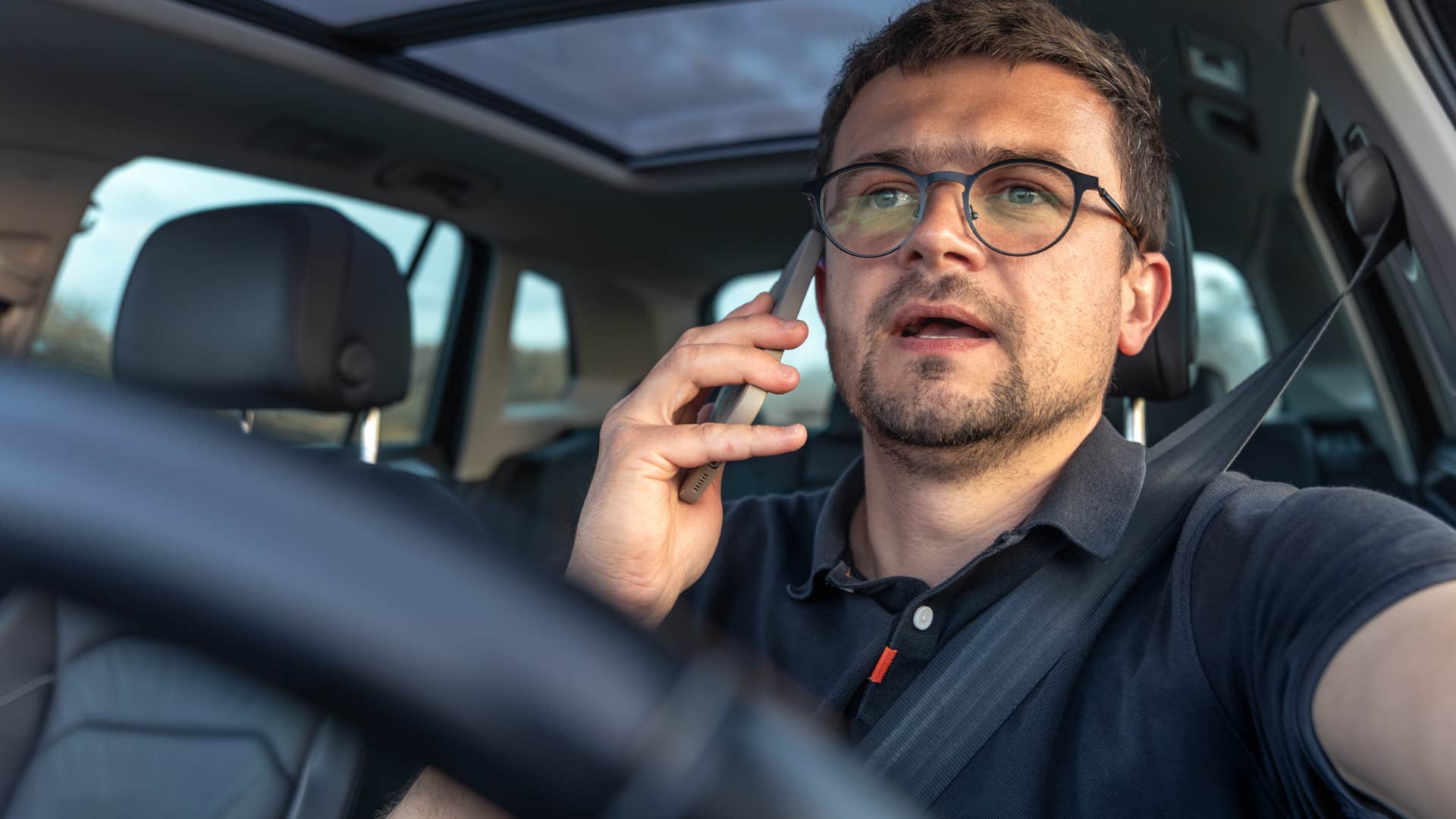Man who's a multitasker talking on the phone while driving.