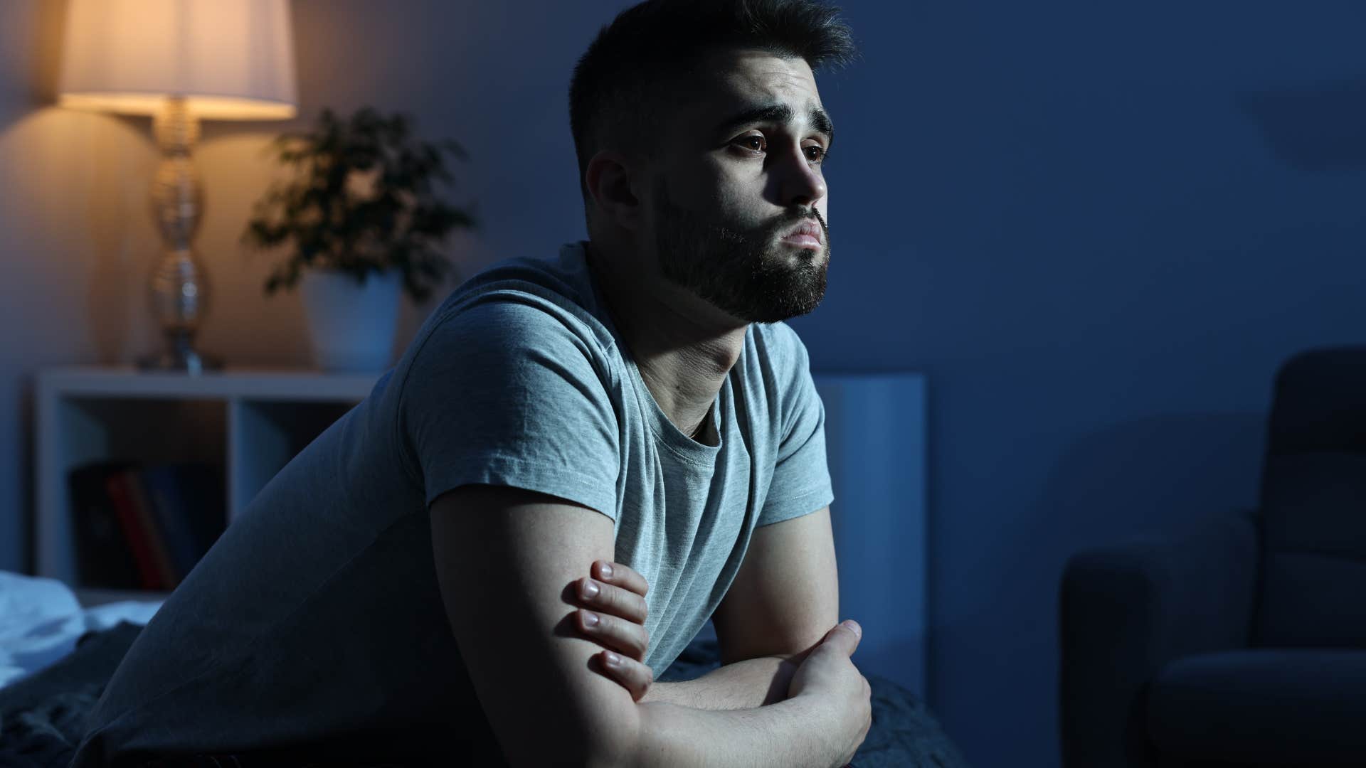 pessimistic man sitting alone at night in bed