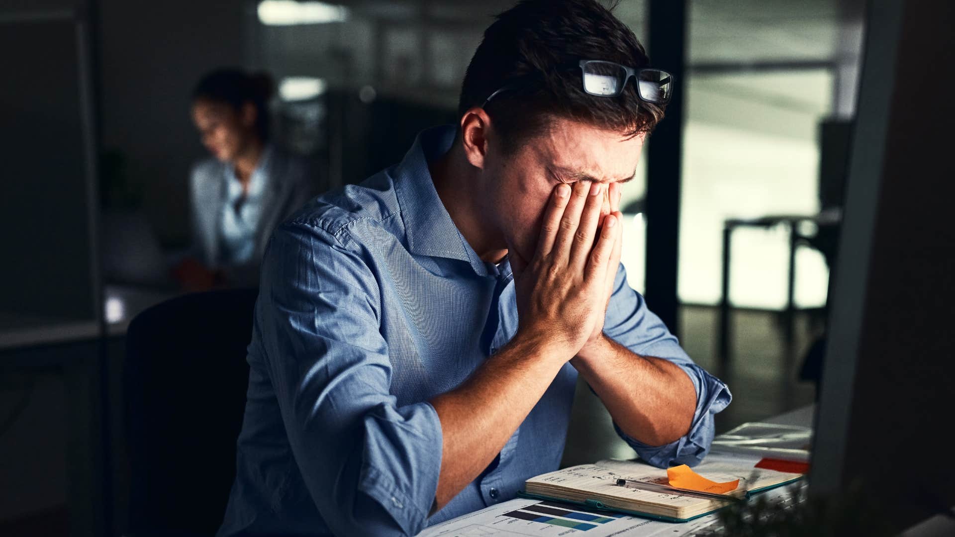 man who's a workaholic sitting at his desk at night overthinking