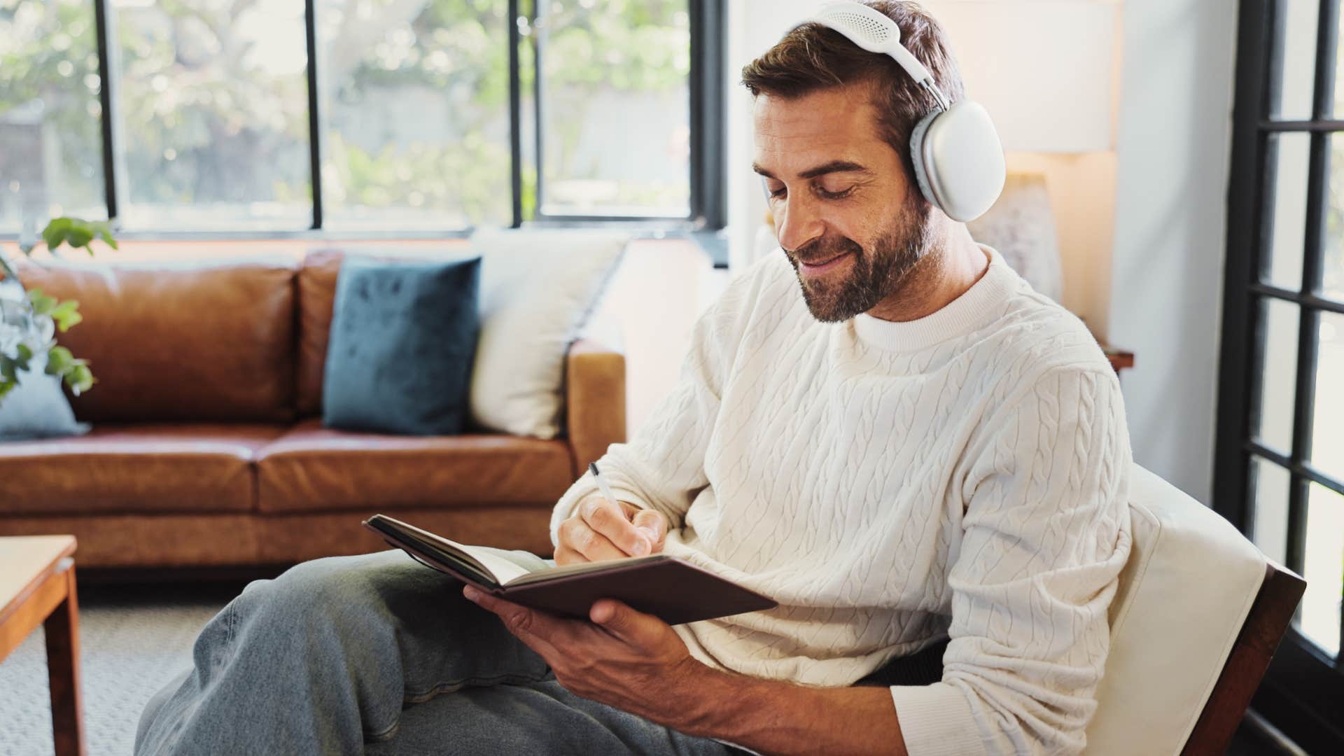 creative man sitting at home reading and listening to music