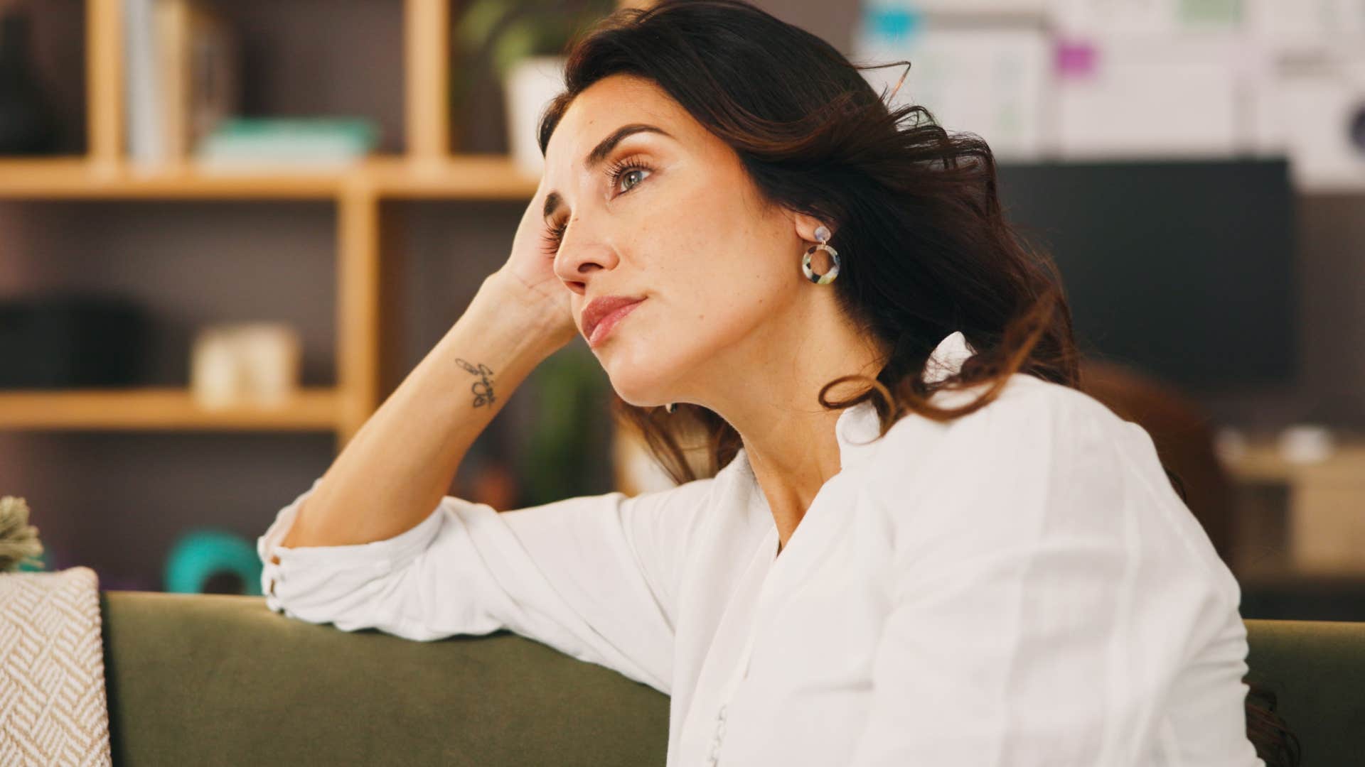 woman who's an overthinker sitting alone at home ignoring knock at the door