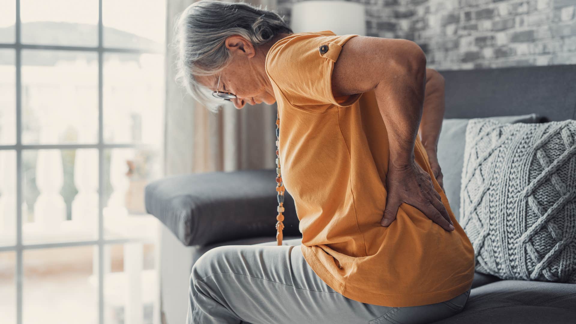 Aging person touches back showing pain