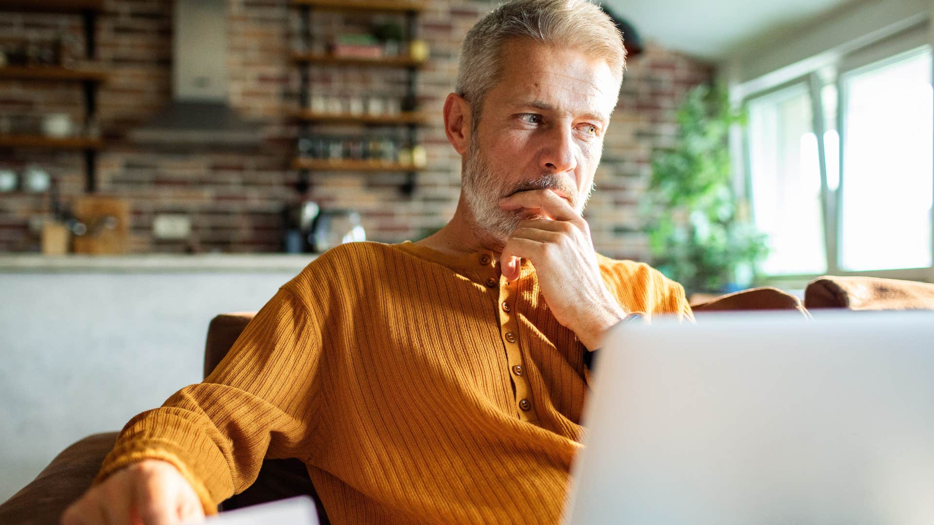 deep thinking man shaking his leg while looking at laptop