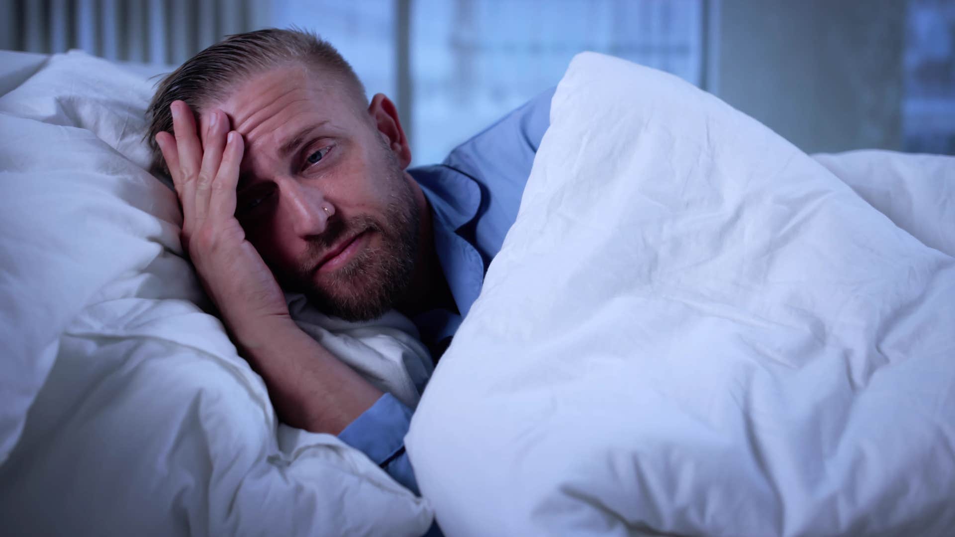 man who struggles to rest lying awake in bed