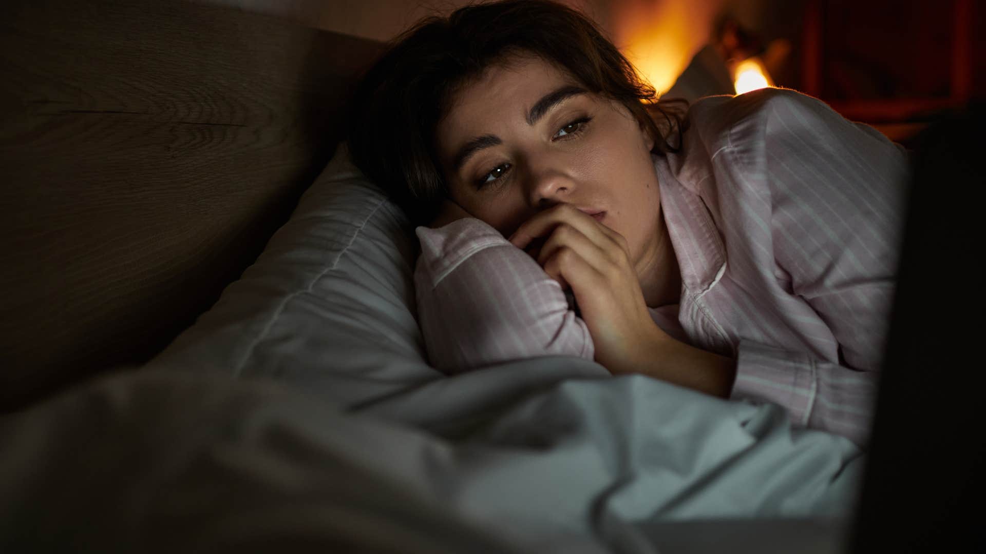 impulsive woman lying and watching TV in bed