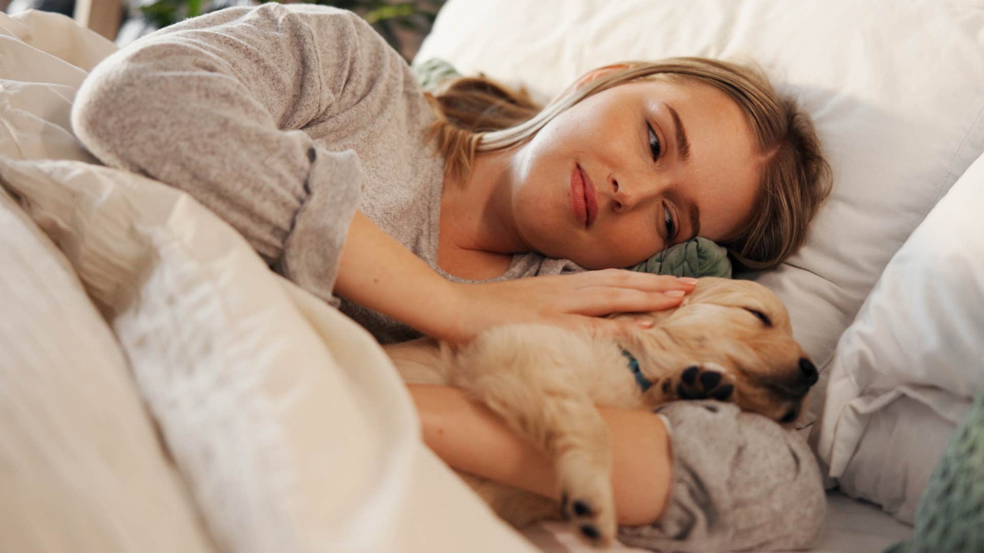 independent woman sleeping with her puppy in bed