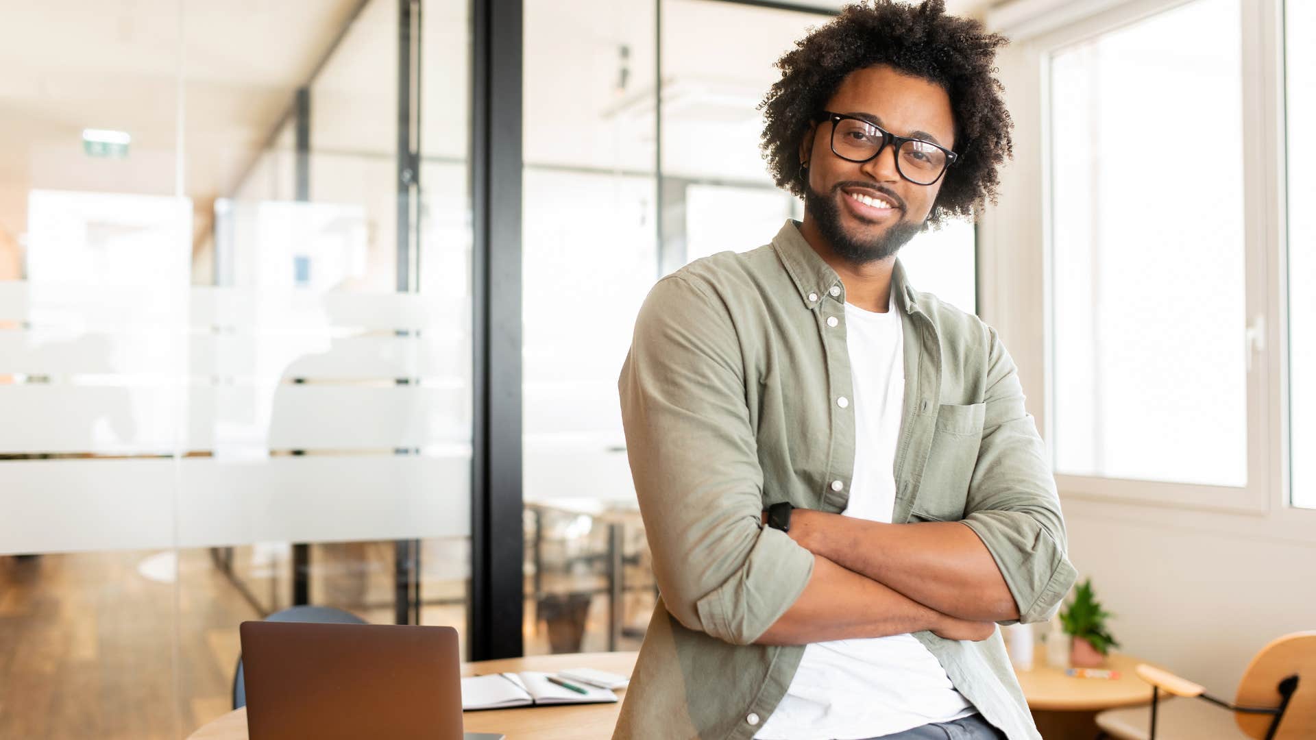 smiling man sitting on desk understanding how tense the world can feel