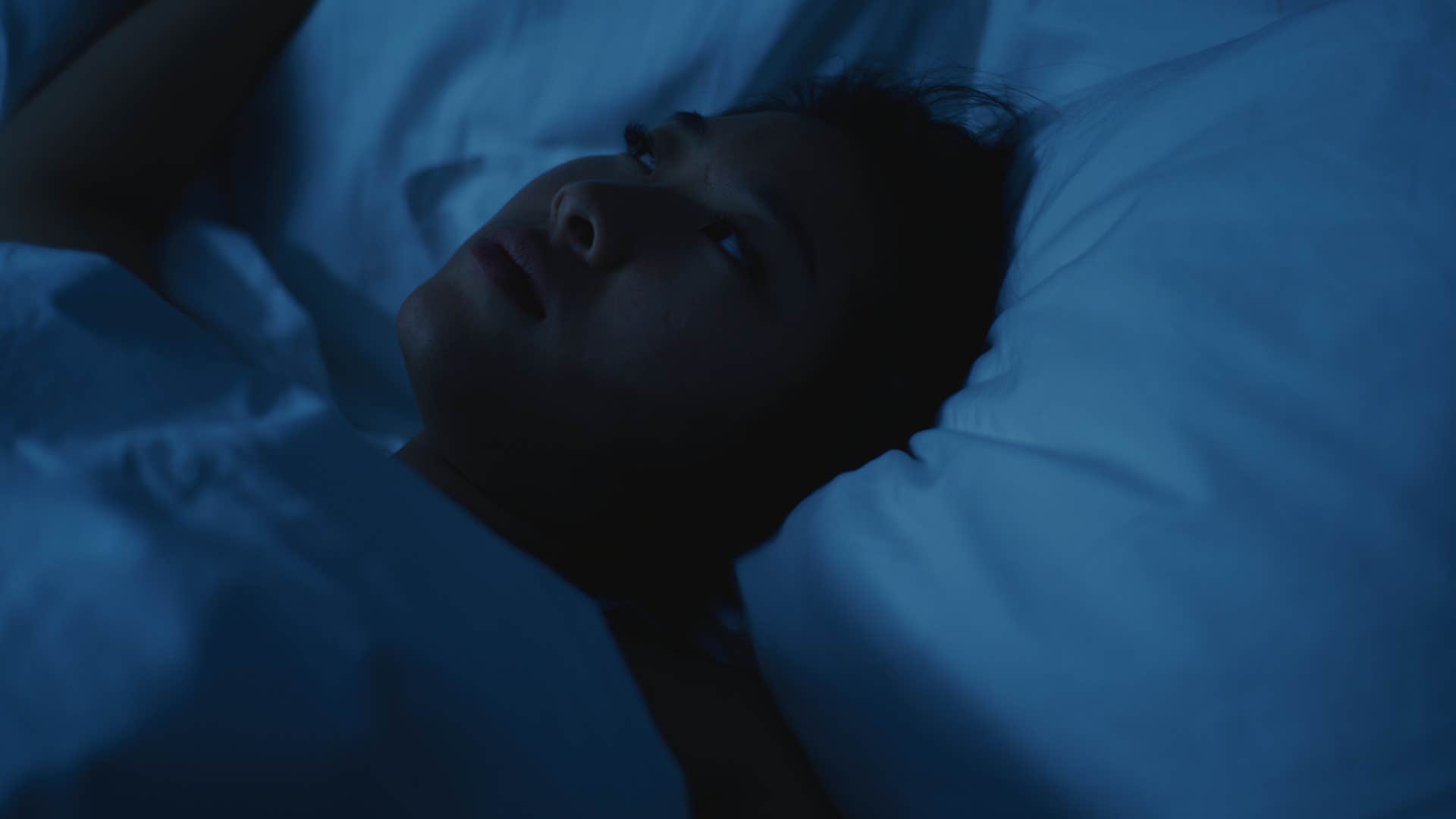 woman who's anxious lying in bed in the dark