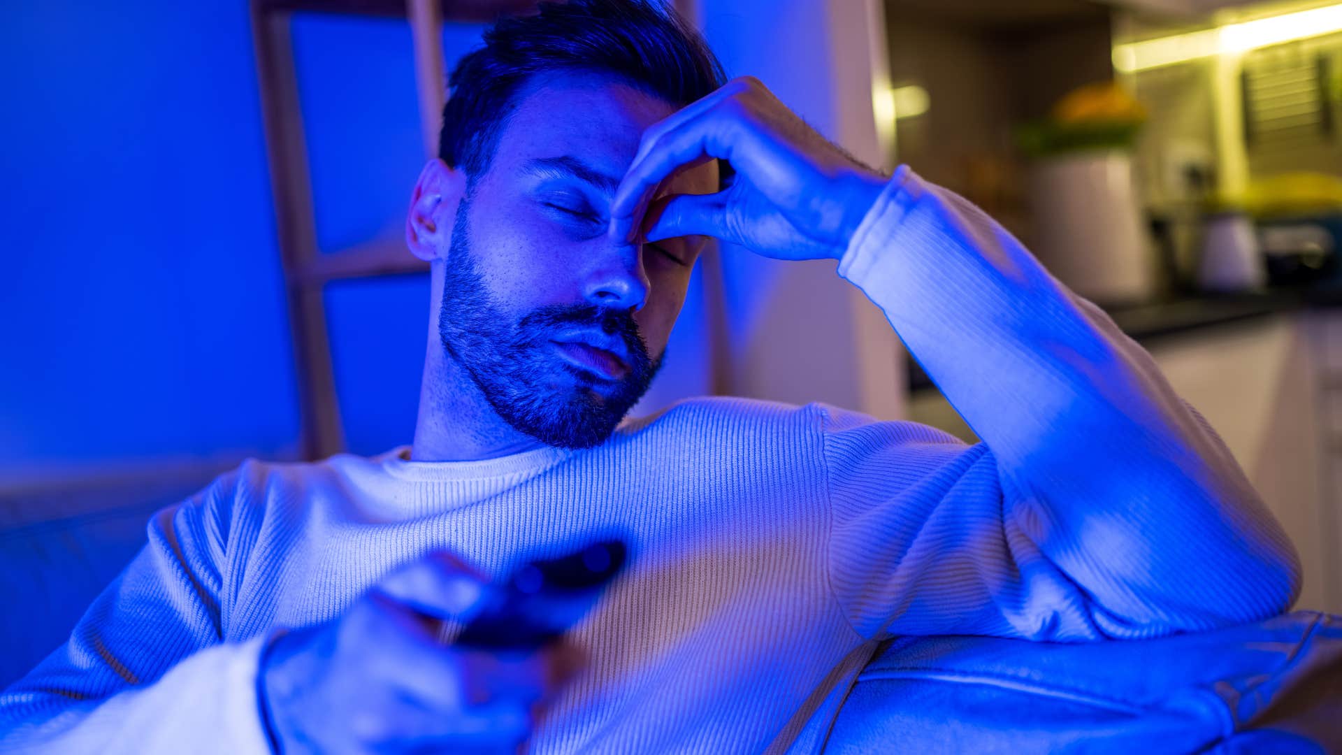 avoidant man sitting on the couch and watching TV in the dark