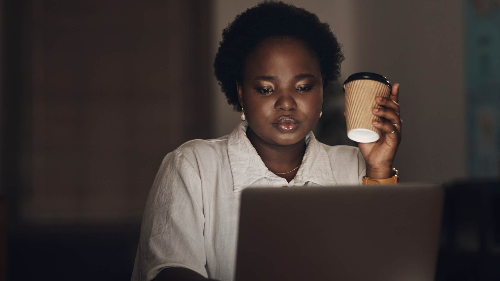 impulsive woman drinking coffee at night while working