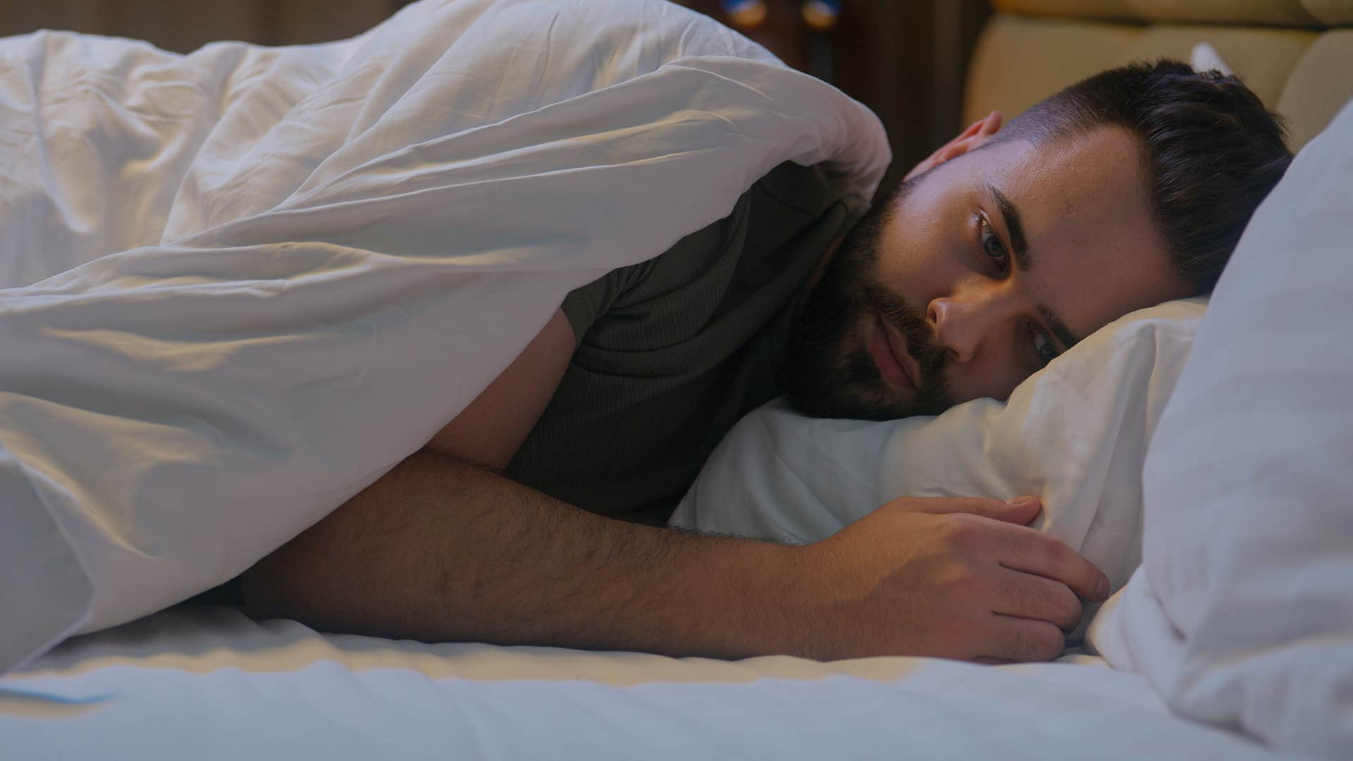 man who's an overthinker lying awake in bed