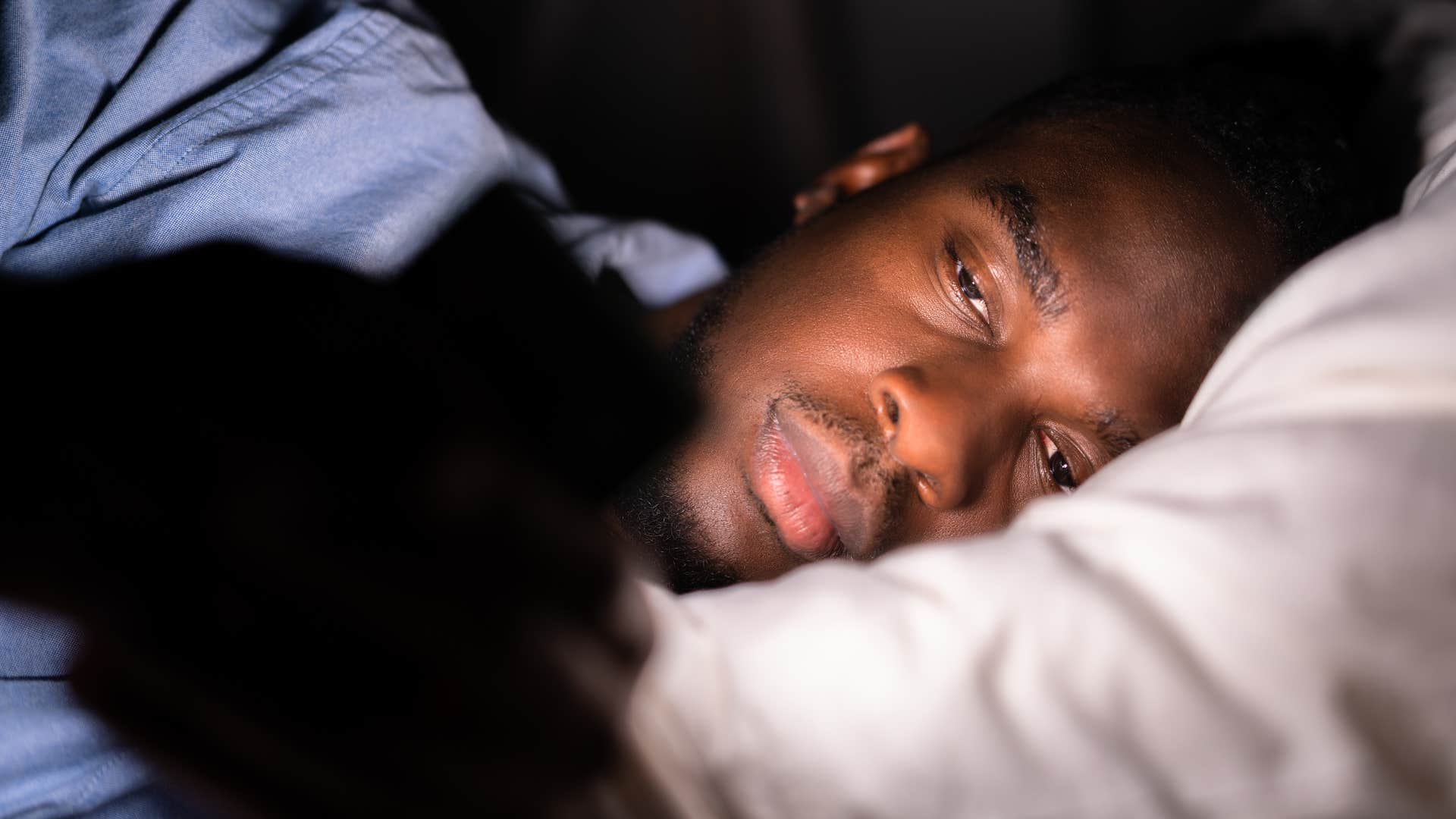 man who wakes up in the middle of the night using his phone in bed