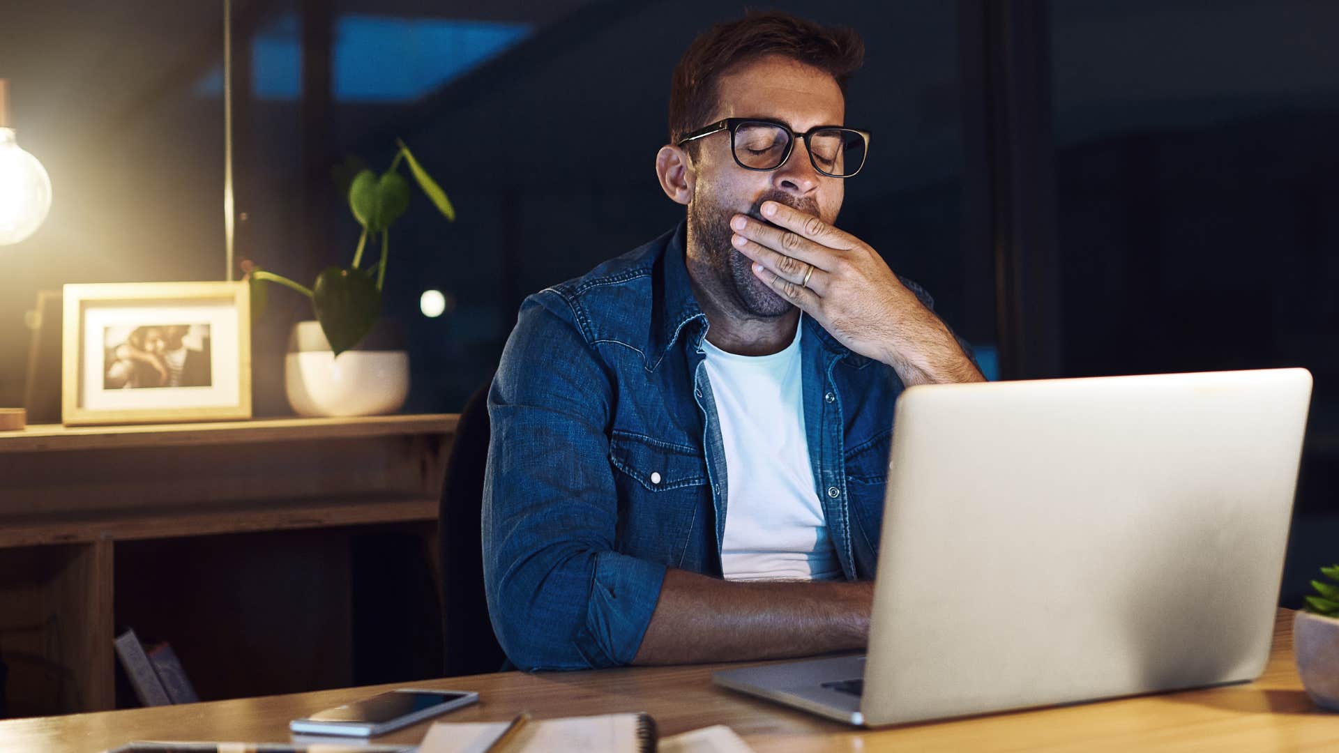 man who's a workaholic sitting at his desk late at night