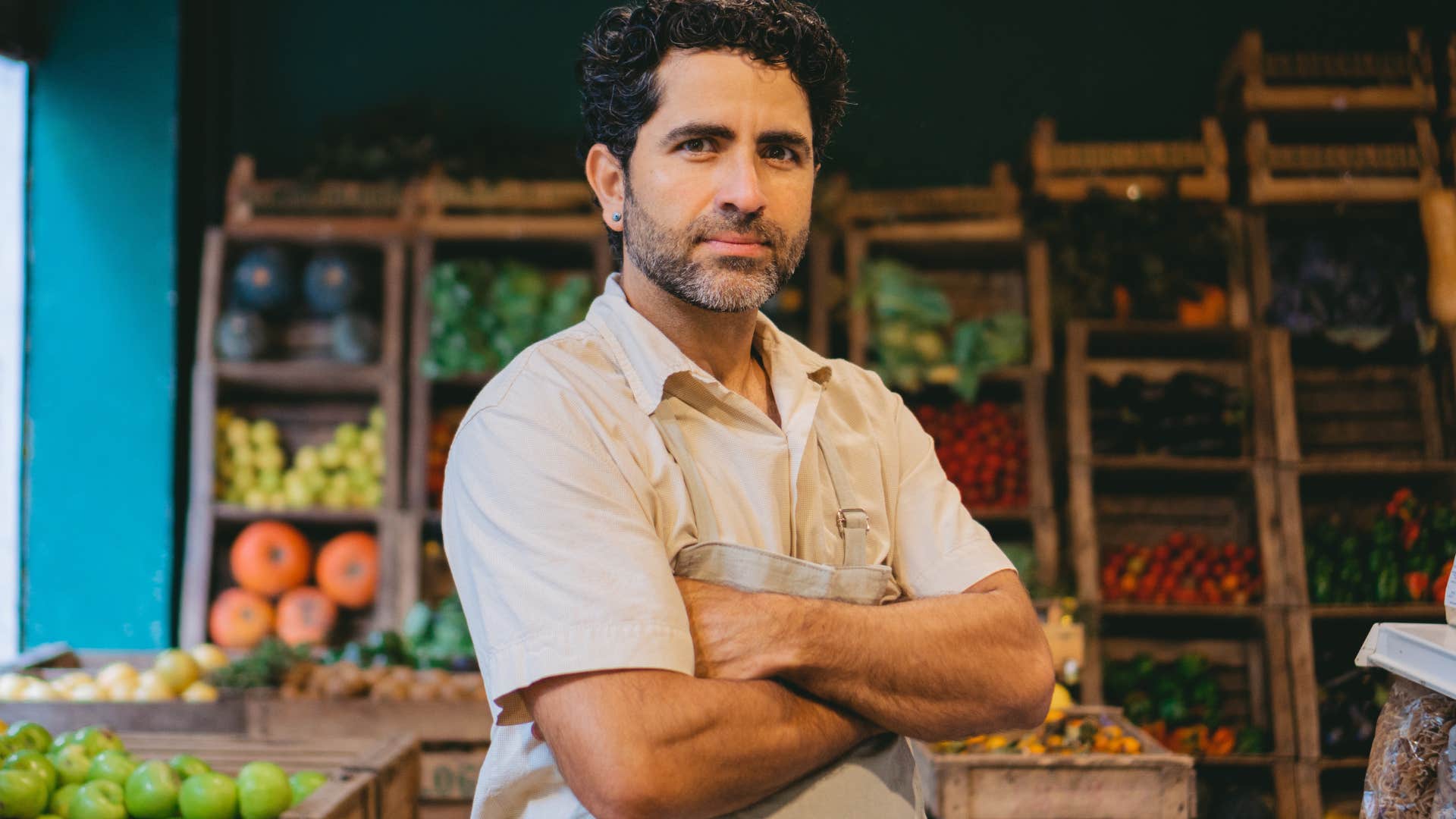 man standing with arms crossed in market