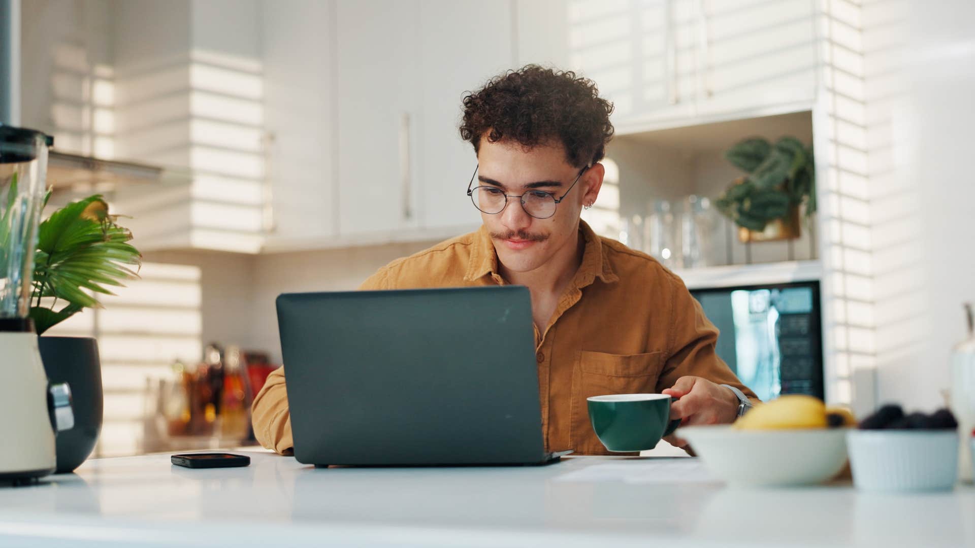 man working on laptop at kitchen table