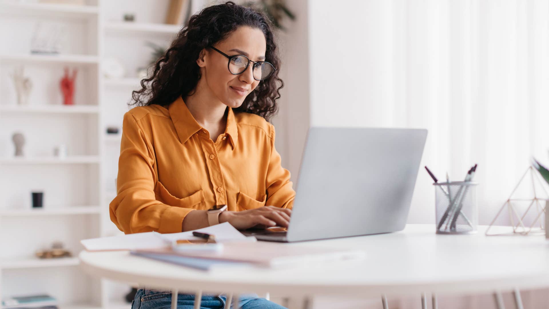 woman in orange on laptop working quickly as she knows a shortcut