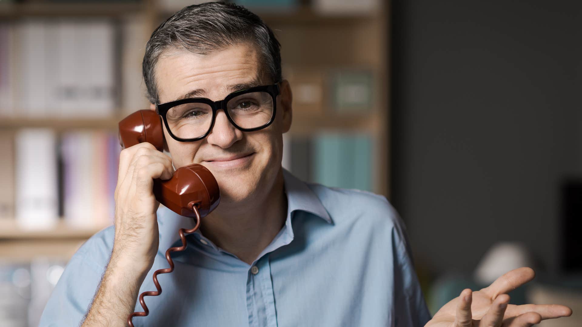 man in blue shirt on phone shrugging as he says that's not my problem