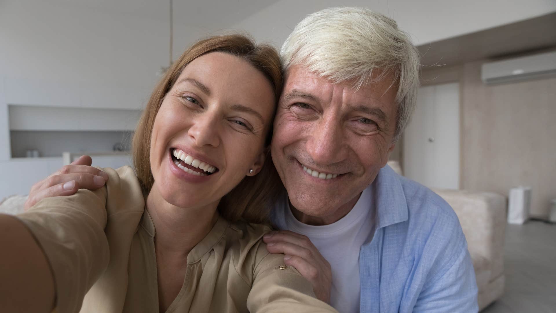 father and adult daughter smiling taking a selfie