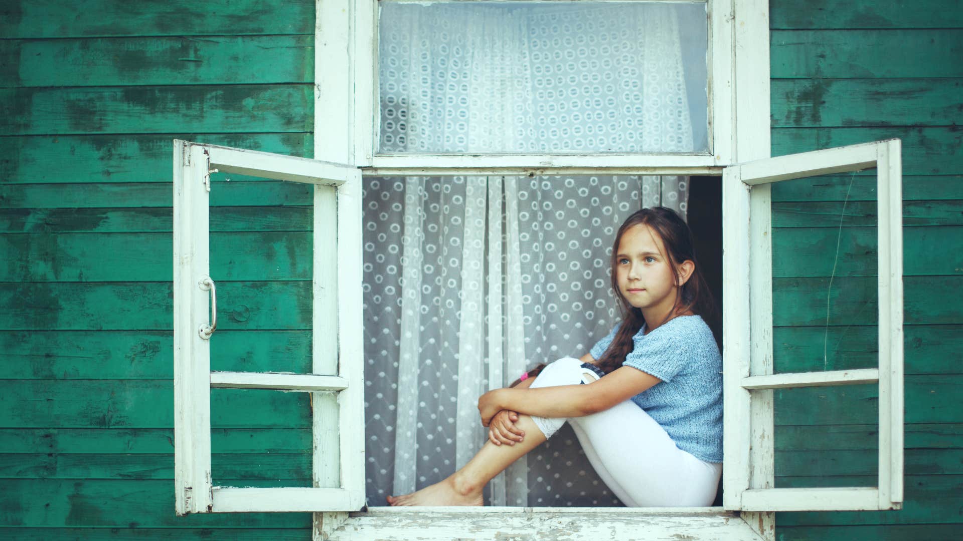 Strong daughter sits in window showing she doesn't need rescuing